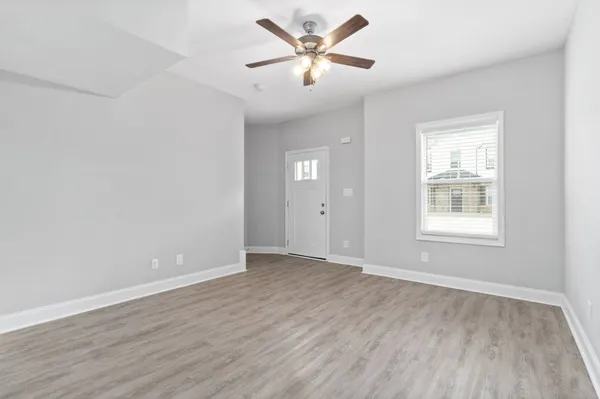 an empty room with wooden floor and windows