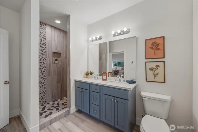 a bathroom with a toilet a sink a glass door shower and a mirror