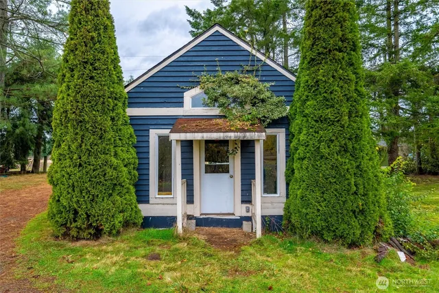 a view of a house with a small yard plants and large tree