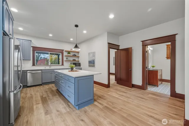 a kitchen with stainless steel appliances granite countertop a refrigerator a sink dishwasher and a refrigerator with wooden floor