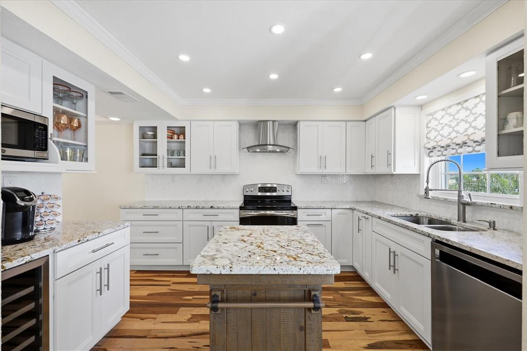9170 Blind Pass Road St. Pete Beach, FL 33706 - Photo 14 of 58 a kitchen with stainless steel appliances granite countertop a stove top oven a sink a window and white cabinets