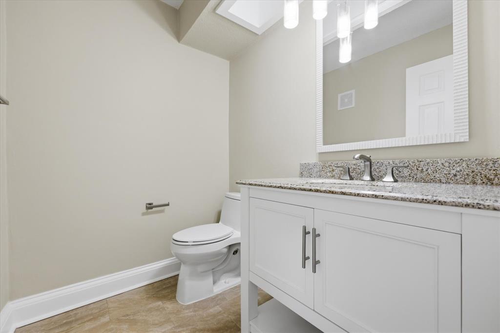 9170 Blind Pass Road St. Pete Beach, FL 33706 - Photo 21 of 58 a bathroom with a granite countertop sink a toilet and a mirror