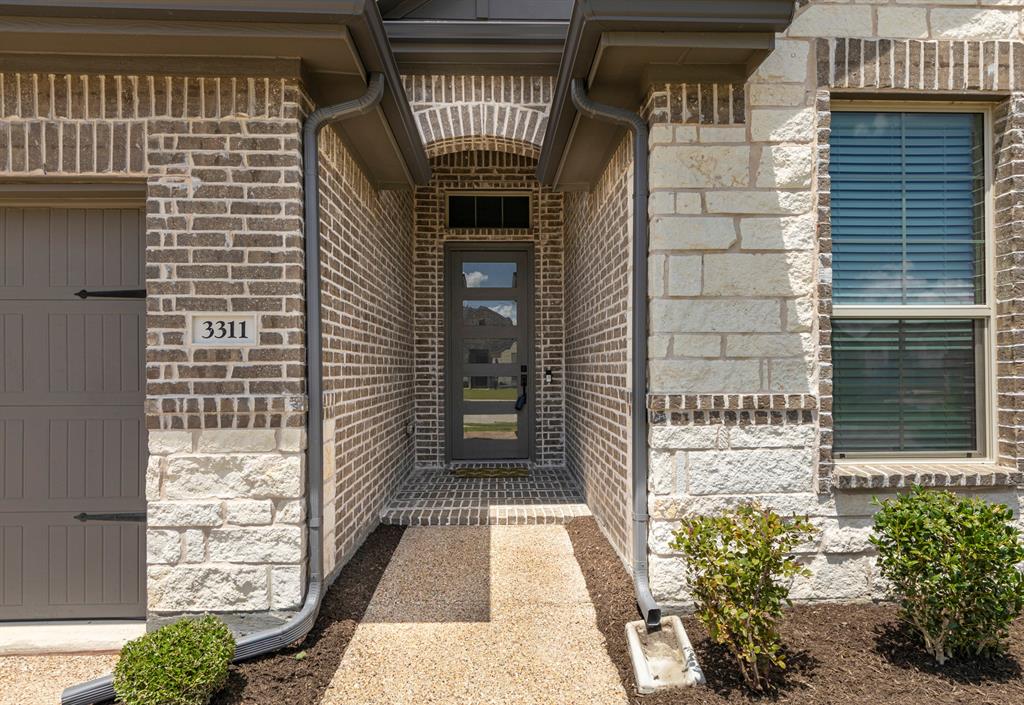 3311 Willena Road Melissa, TX 75454 - Photo 5 of 40 Modern exterior featuring a brick and stone facade, covered entryway, and a contemporary glass-paneled front door