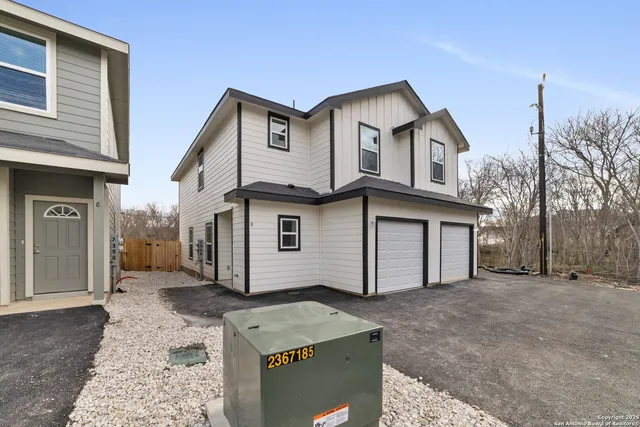 a view of a white house with a large tree