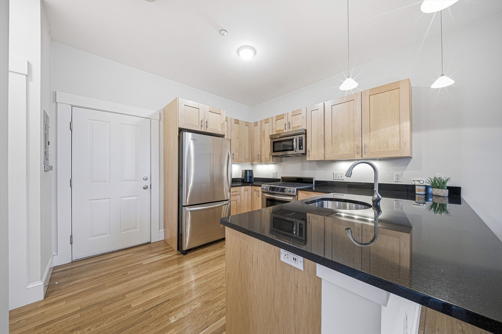 190 Prospect Street, Unit 8 Cambridge, MA 02139 - Photo 6 of 32 a kitchen with stainless steel appliances granite countertop a refrigerator a sink dishwasher a stove and white cabinets with wooden floor