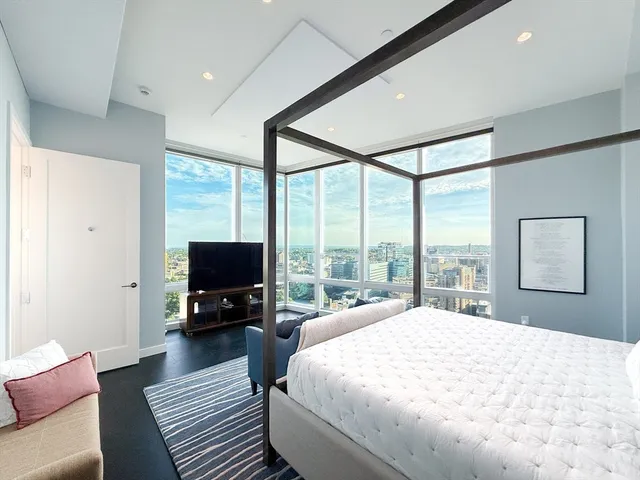 a spacious bedroom with a large bed and a flat tv screen
