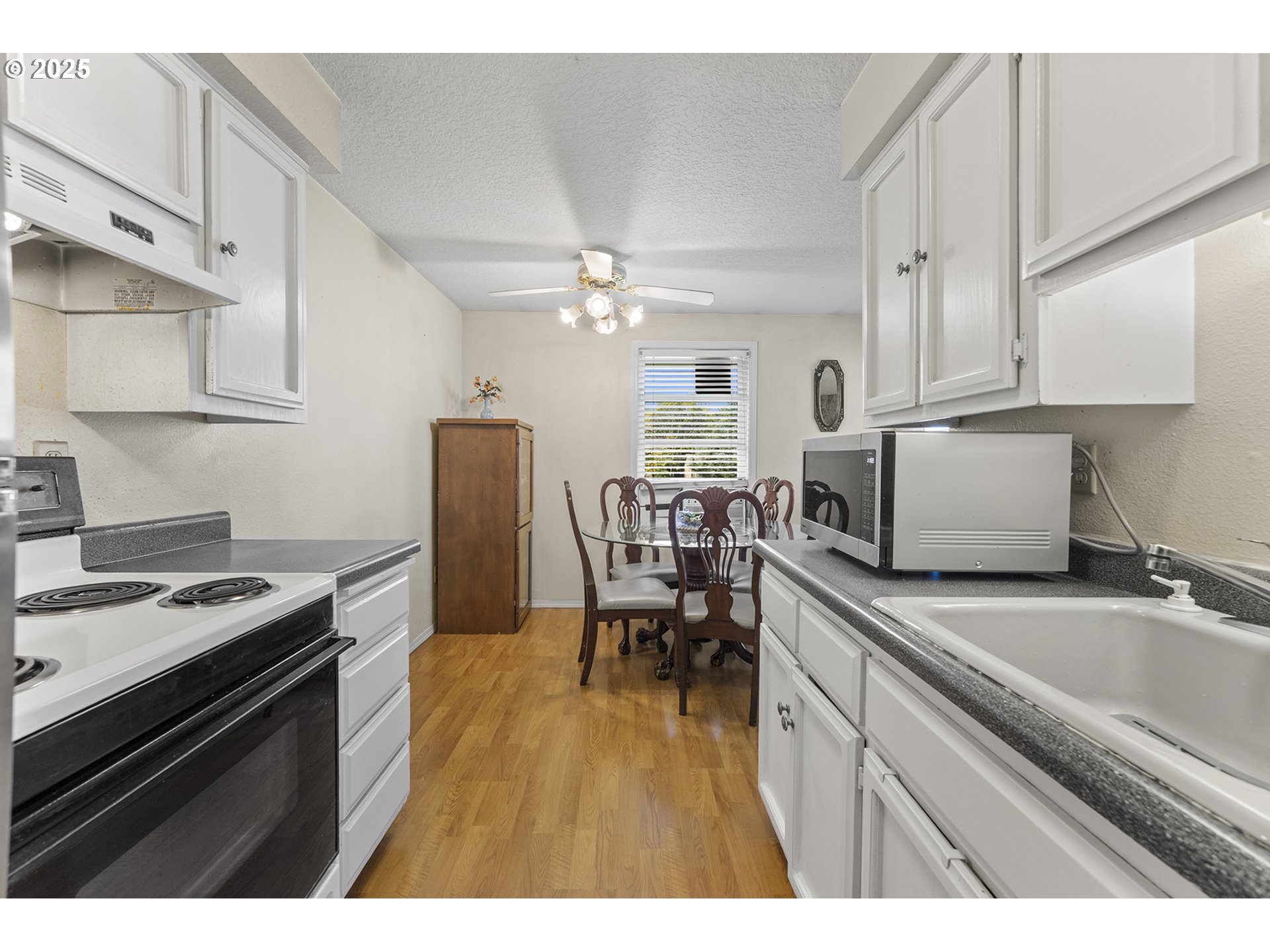 8512 Southwest Mohawk Street Tualatin, OR 97062 - Photo 14 of 33 a kitchen with stainless steel appliances granite countertop a stove a sink dishwasher and white cabinets with wooden floor