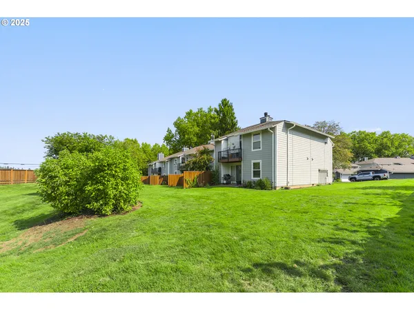 a view of a big house with a big yard plants and large trees