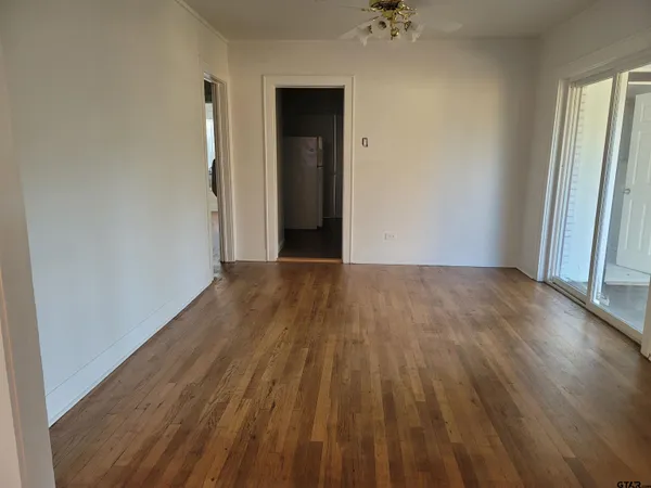 a view of a room with wooden floor and a ceiling fan