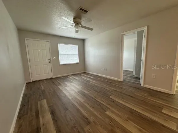a view of an empty room with wooden floor and window