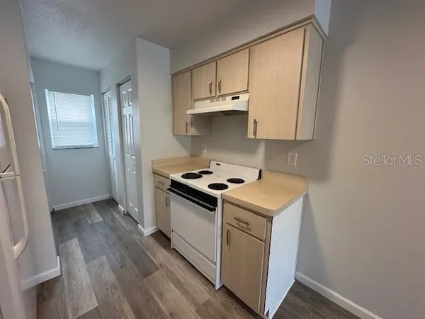 a kitchen with a stove and a wooden floor