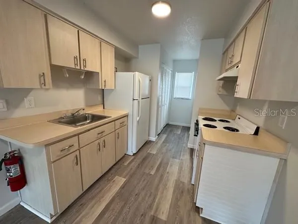 a kitchen with refrigerator a stove a sink dishwasher and white cabinets with wooden floor