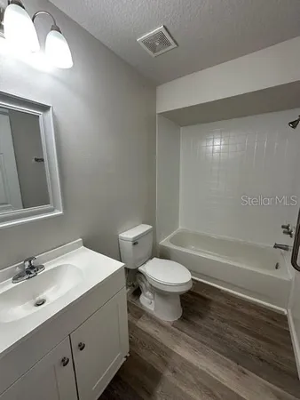 a bathroom with a bathtub shower sink vanity mirror and toilet