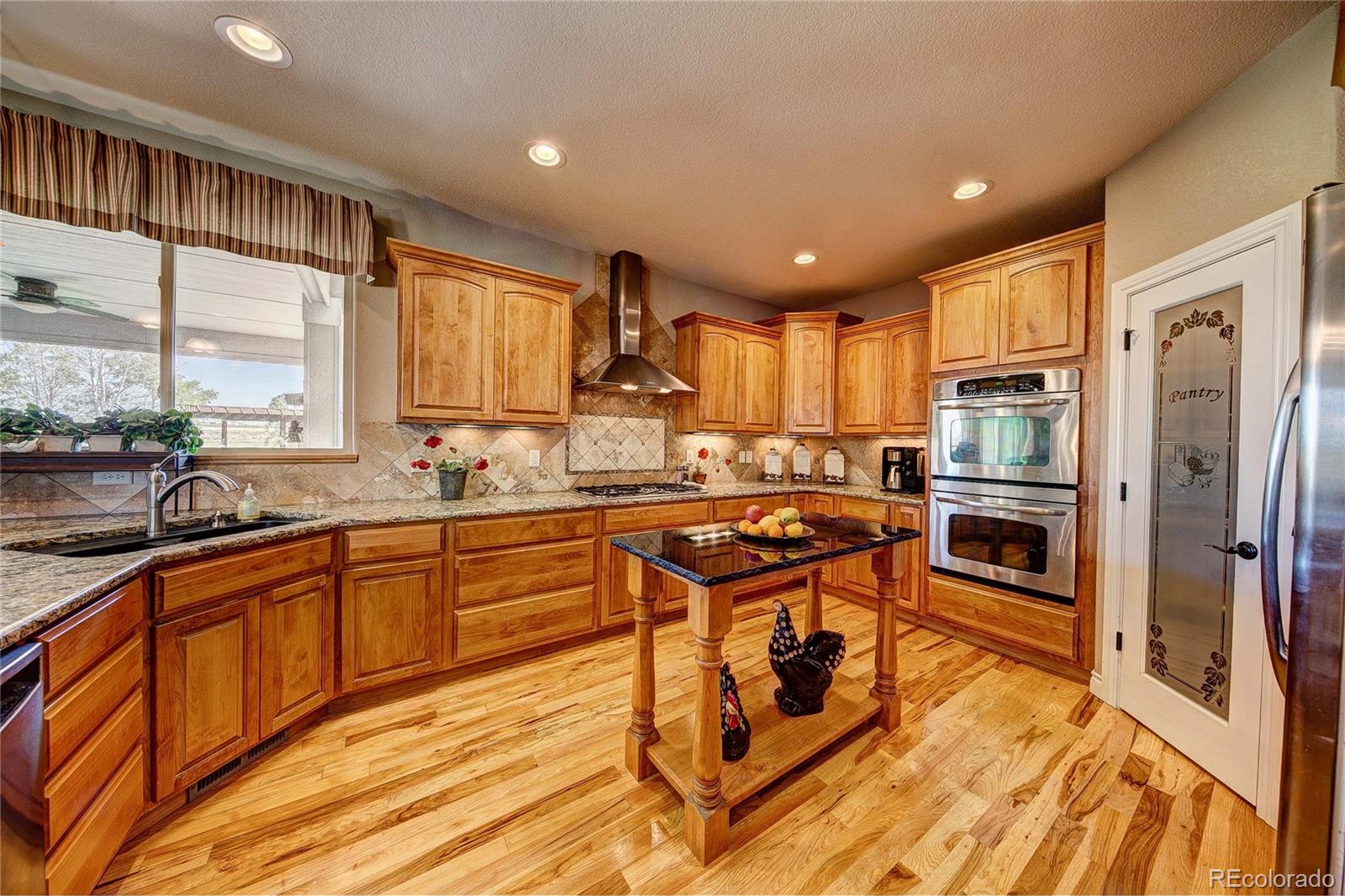 37053 Soaring Eagle Circle Severance, CO 80550 - Photo 14 of 35 a kitchen with stainless steel appliances granite countertop a stove top oven a sink dishwasher a refrigerator and cabinets with wooden floor