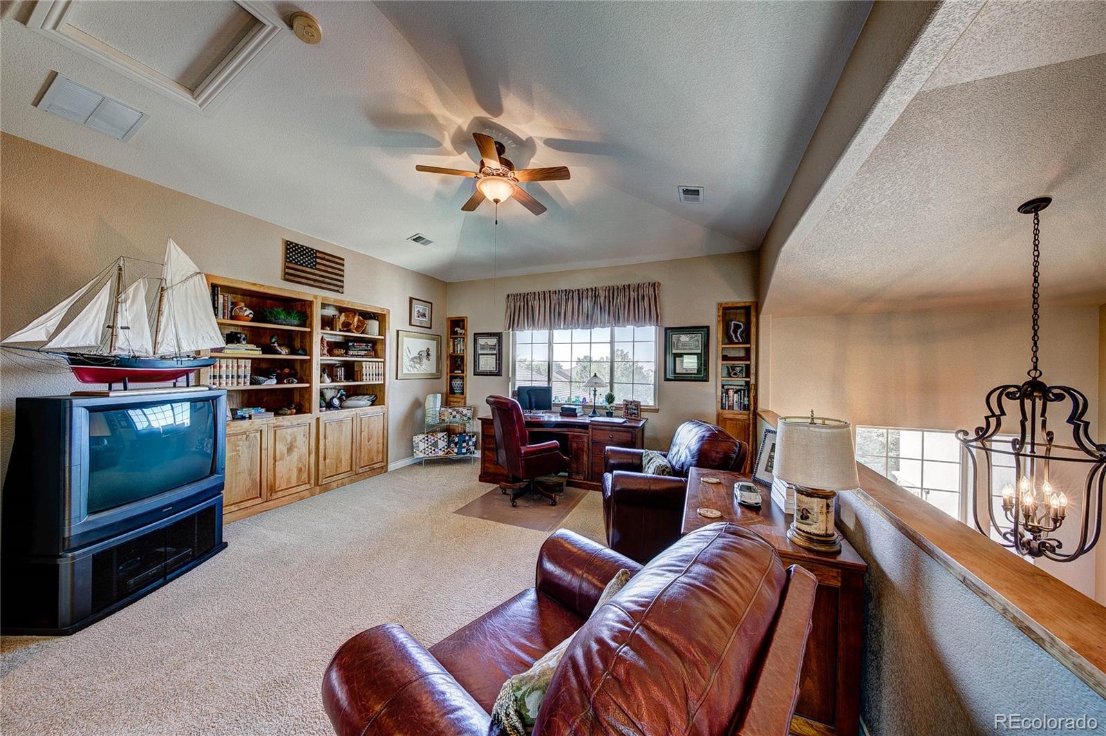 37053 Soaring Eagle Circle Severance, CO 80550 - Photo 23 of 35 a living room with furniture a ceiling fan and a book shelf