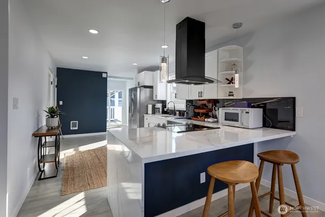 a kitchen with stainless steel appliances kitchen island granite countertop a sink chairs and refrigerator