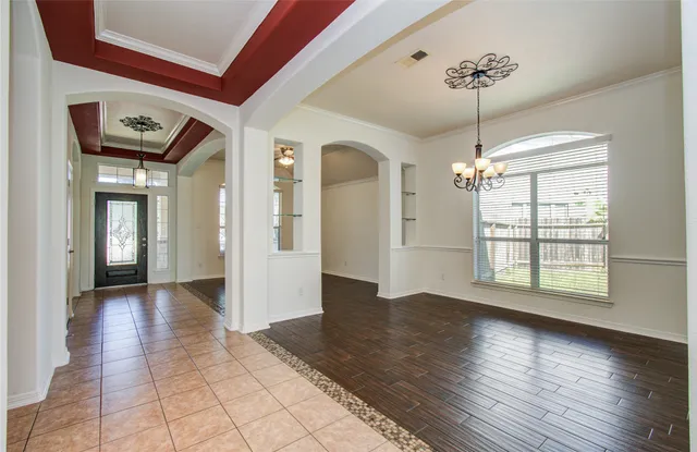 a view of a room with wooden floor chandelier and windows