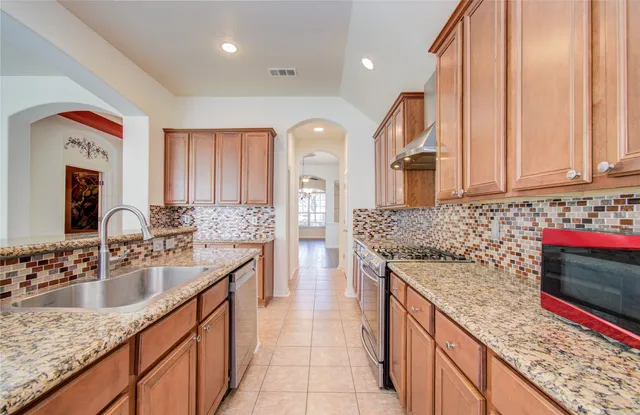 a kitchen with stainless steel appliances granite countertop a sink stove and cabinets