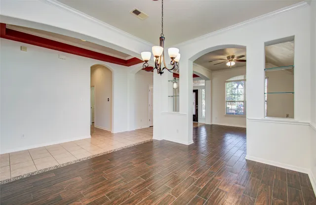 a view of a big room with wooden floor a chandelier and windows