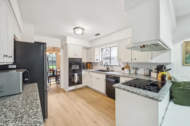 a kitchen with a refrigerator a stove a sink dishwasher and wooden cabinets with wooden floor