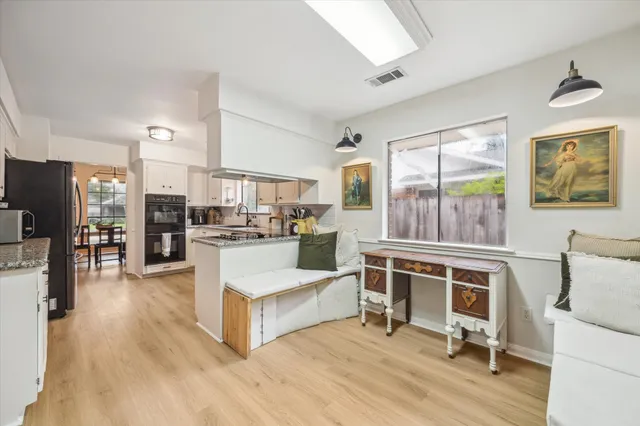 a living room with stainless steel appliances furniture and a kitchen view