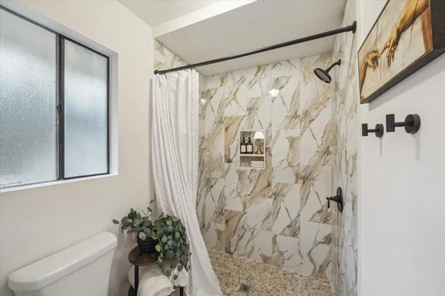 a bathroom with a shower curtain a mirror a sink and a shower