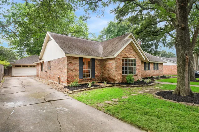 a front view of a house with a garden and trees