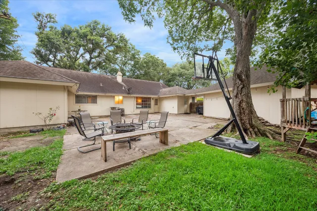 a view of a backyard with table and chairs potted plants and a large tree