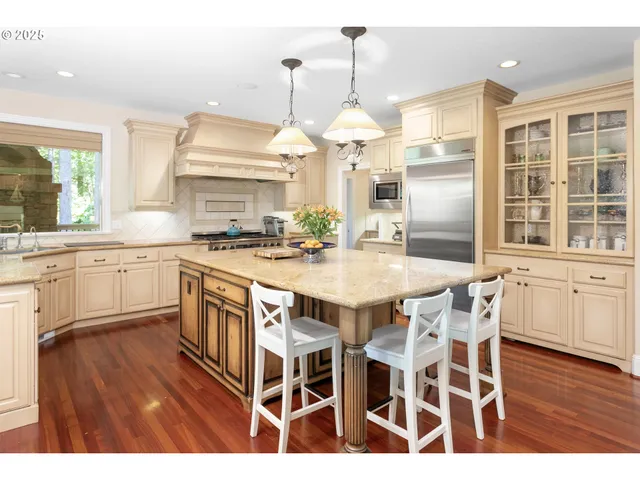 a kitchen with stainless steel appliances a dining table chairs and wooden floor