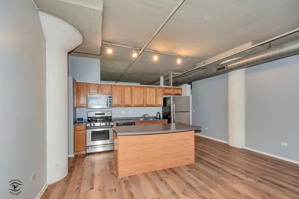 a kitchen with stainless steel appliances granite countertop a refrigerator a stove and a sink with wooden floor