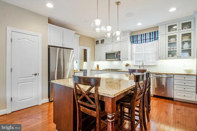 a kitchen with stainless steel appliances granite countertop a dining table chairs refrigerator and microwave