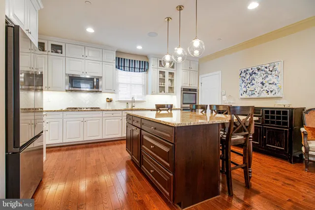 a open kitchen with stainless steel appliances granite countertop a stove top oven a refrigerator and a dining table with wooden floor