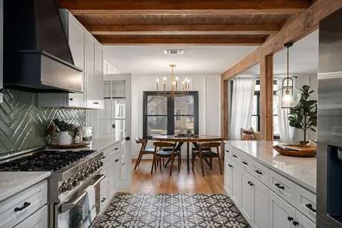 a kitchen with granite countertop a stove a sink a dining table and chairs