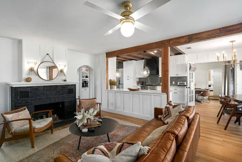 a living room with furniture a fireplace and a large mirror with wooden floor