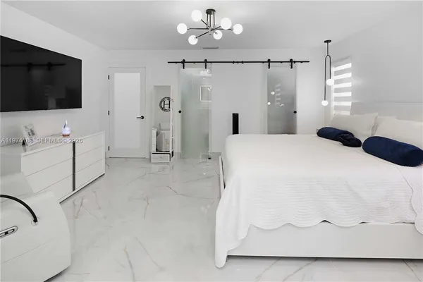 a large white bathroom with a bathtub and a flat screen tv