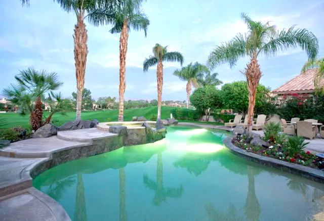 a view of a lake with a lawn chairs under palm trees