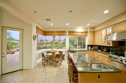 a view of a kitchen with kitchen island a large window cabinets and stainless steel appliances