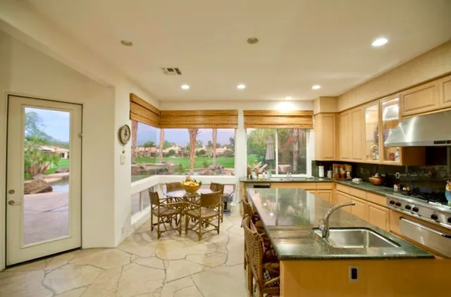 a view of a kitchen with kitchen island a large window cabinets and stainless steel appliances