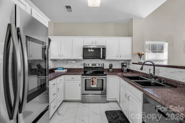a kitchen with granite countertop a sink stove and refrigerator