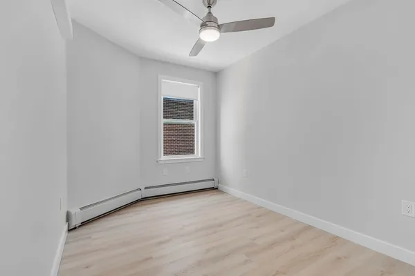 an empty room with windows and fan