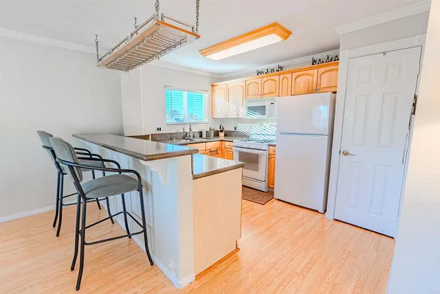 a kitchen with stainless steel appliances granite countertop a refrigerator a stove a sink dishwasher and a dining table with wooden floor