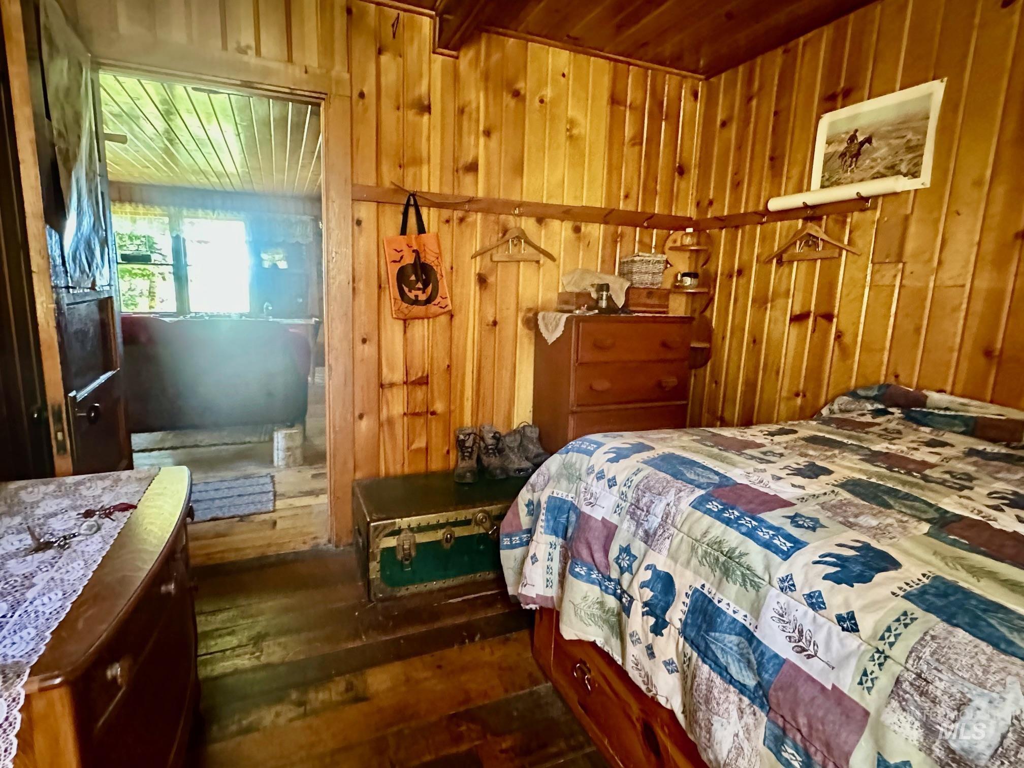 509 Deadline Road, Unit 2 Twin Falls, ID 83301 - Photo 16 of 28 Wood-paneled room featuring wood-finish flooring, a wood-paneled ceiling, and a doorway opening to another room