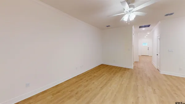 an empty room with wooden floor and fan