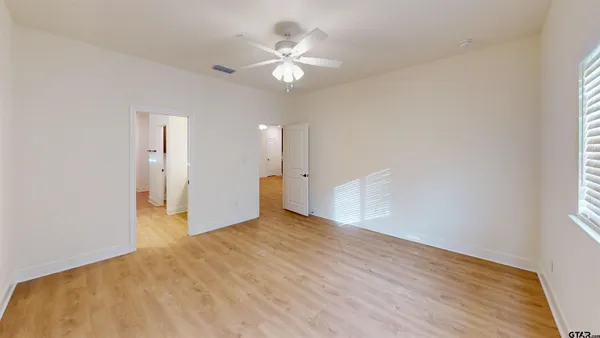 an empty room with wooden floor and ceiling fan