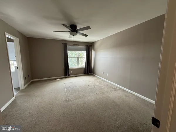 an empty room with windows and chandelier fan