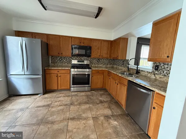 a kitchen with stainless steel appliances granite countertop a sink stove refrigerator and microwave