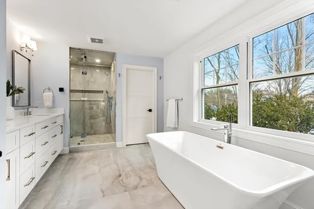 a spacious bathroom with a tub sink shower and mirror