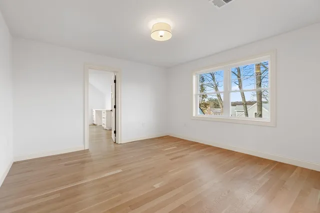 a view of an empty room with wooden floor and a bathroom