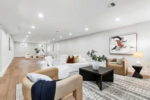 a living room with a couch and potted plant with wooden floor
