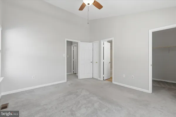 a view of an empty room and chandelier fan